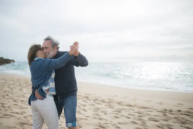 Couple de senior qui danse sur la plage avec mer en arrière-plan,
