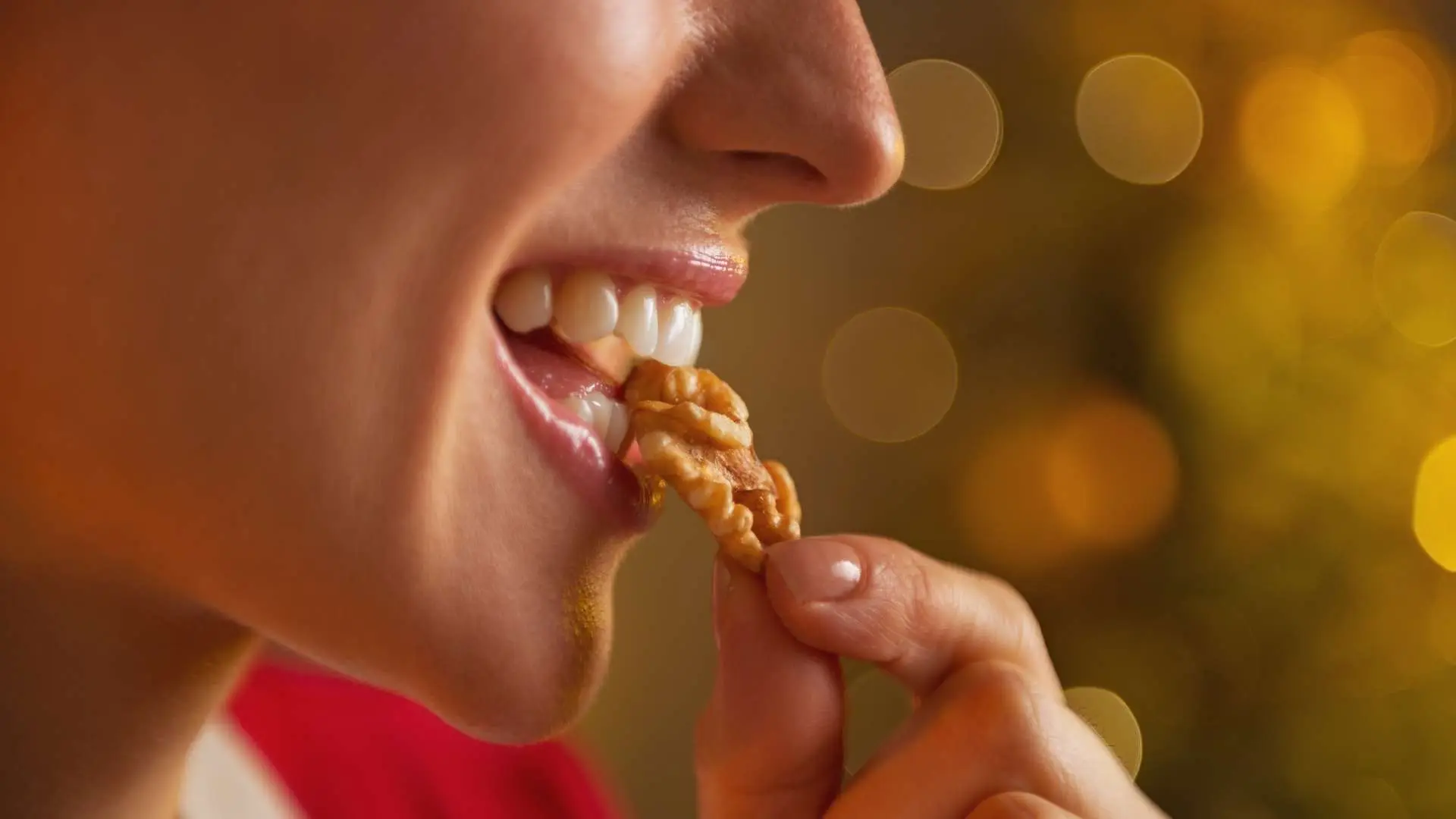 Visage de femme de profil qui tient une noix dans sa bouche